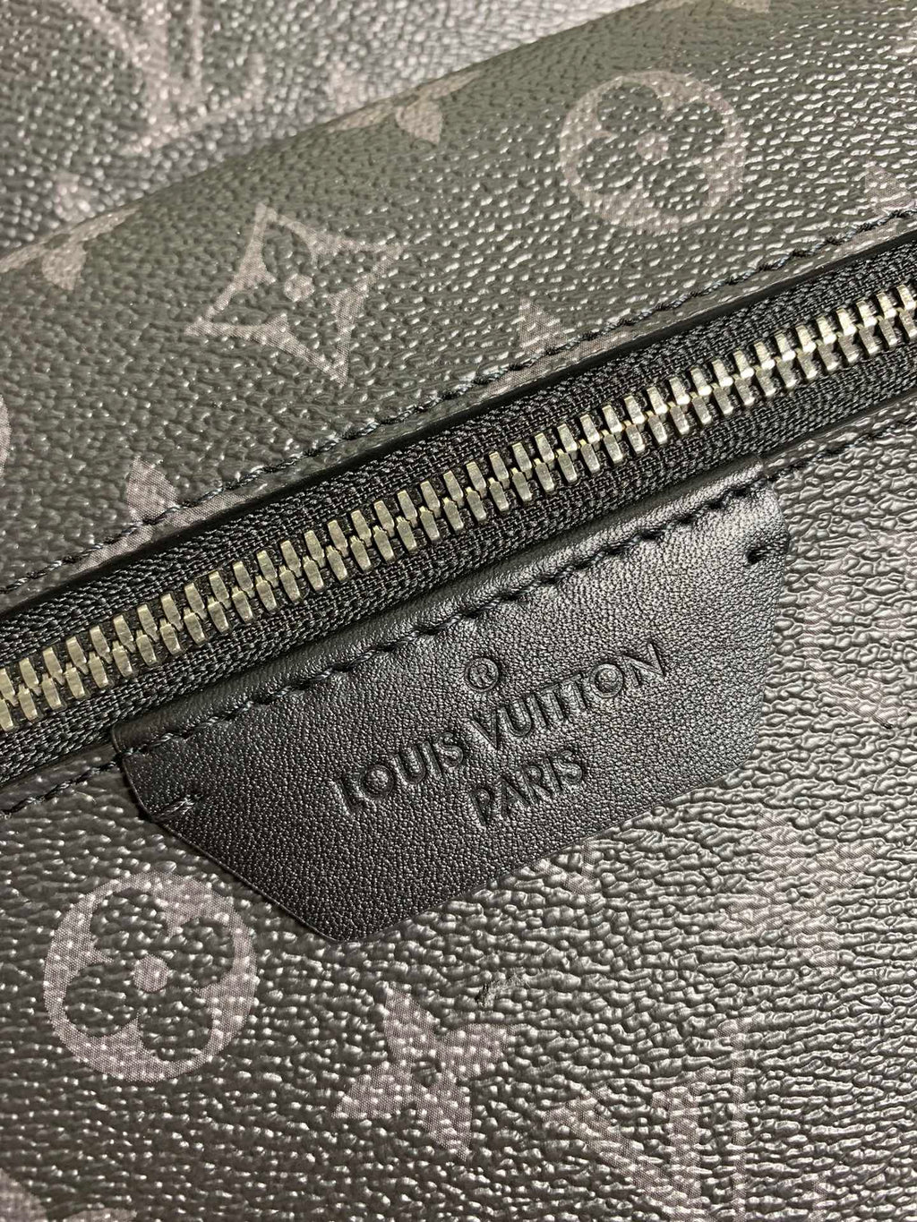 Monogram bag leather label patch near zipper with engraved Louis Vuitton text