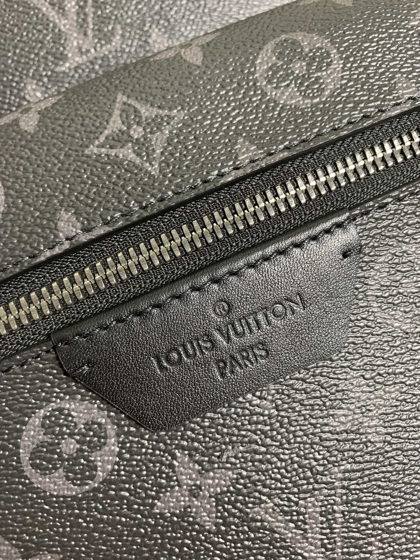 Monogram bag leather label patch near zipper with engraved Louis Vuitton text