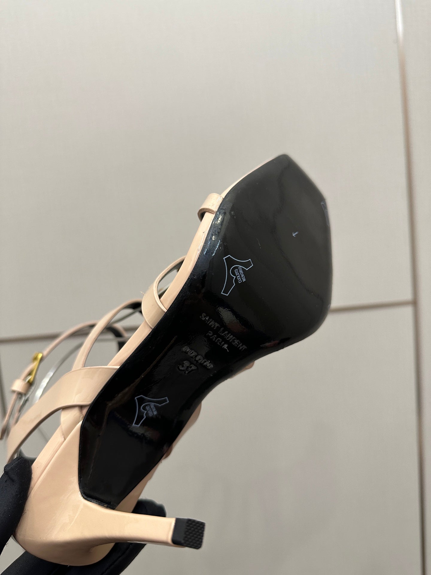 Beige high-heel sandal with black outsole and open toe underside view.