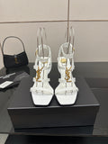 White high-heel strappy sandals with gold-tone hardware, open toe and thin ankle straps.