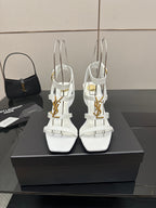 White high-heel strappy sandals with gold-tone hardware, open toe and thin ankle straps.