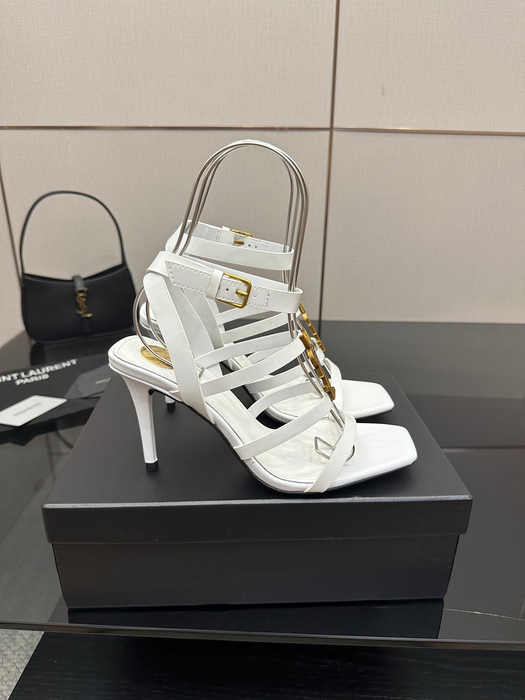 White open-toe high-heel sandals with thin straps and gold-tone buckle detail.