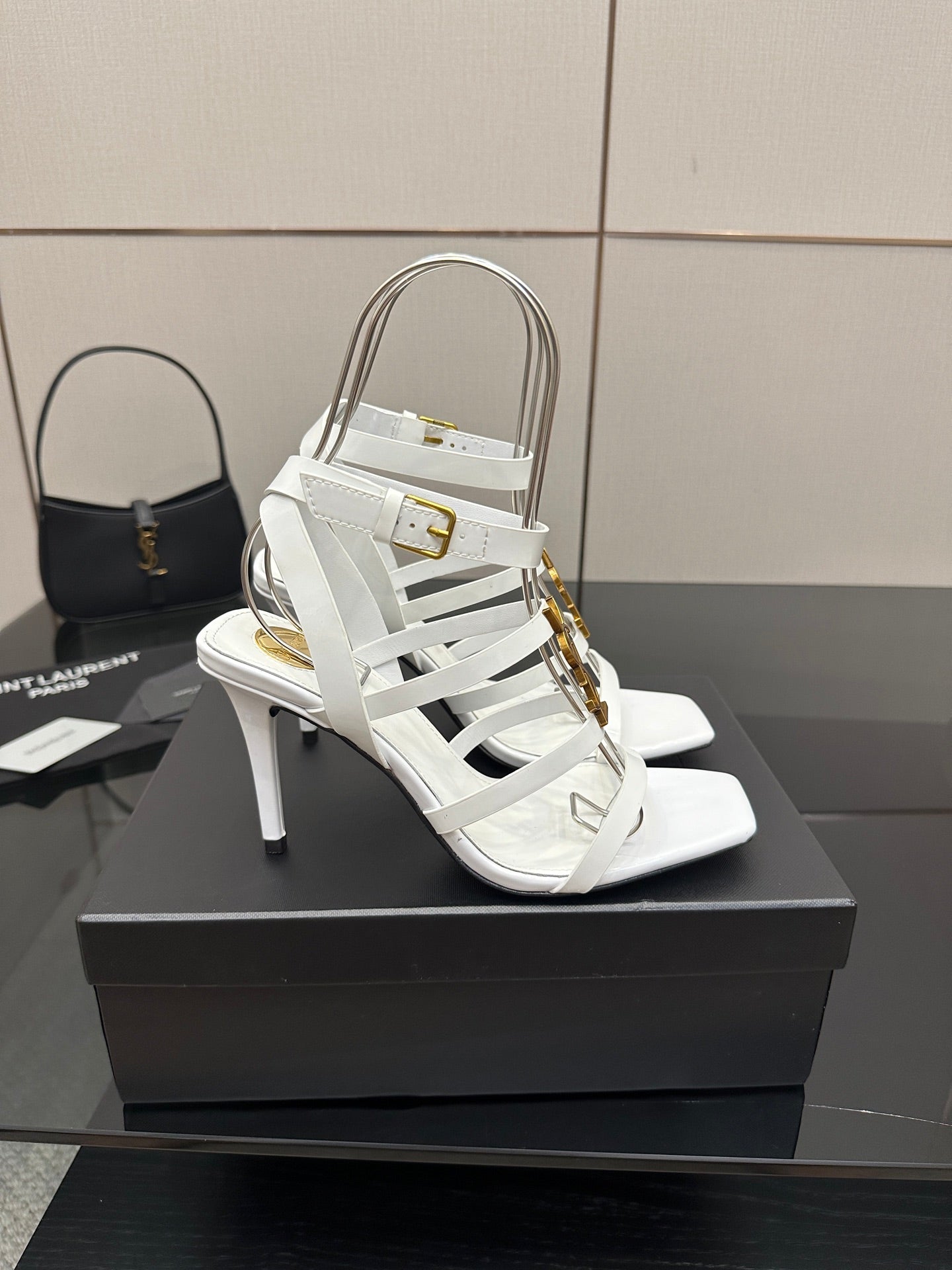 White open-toe high-heel sandals with thin straps and gold-tone buckle detail.