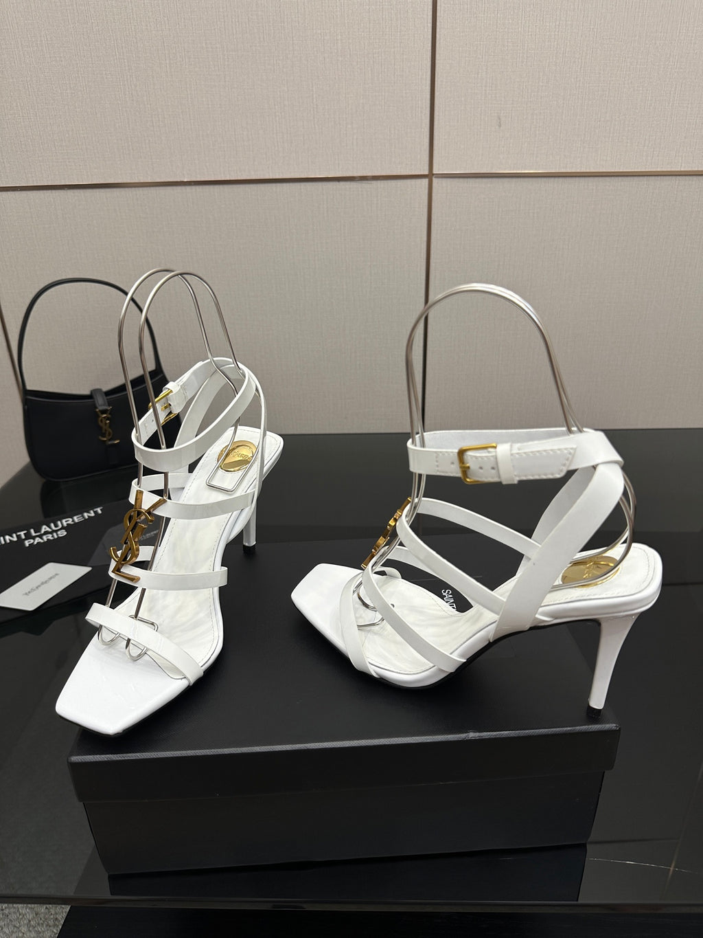 White high-heel sandals with wide strap across the foot and gold-tone hardware, side view.