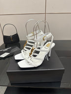 White strappy high-heel sandals with crisscross straps and gold-tone accents on the side.