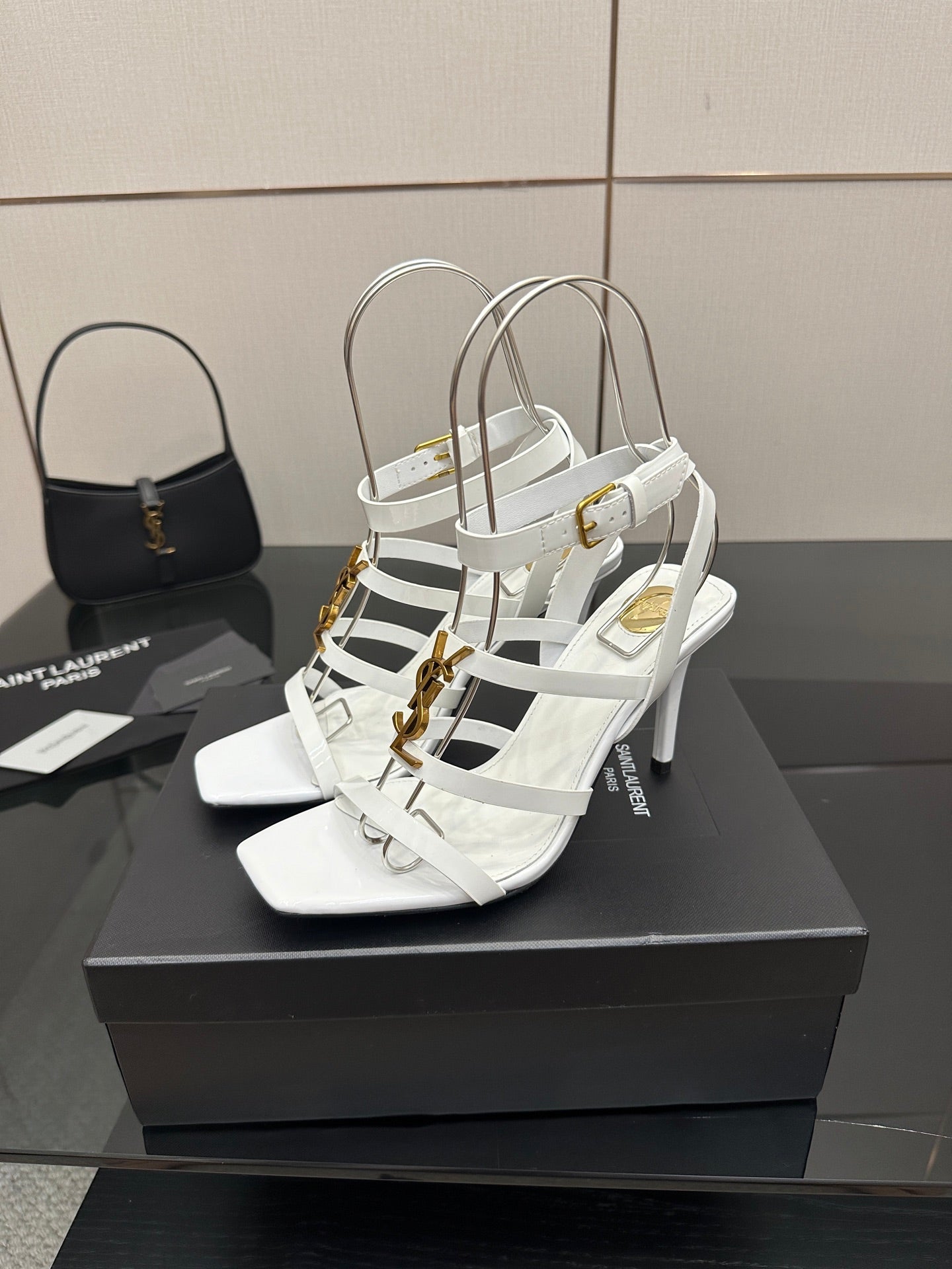 White strappy high-heel sandals with crisscross straps and gold-tone accents on the side.