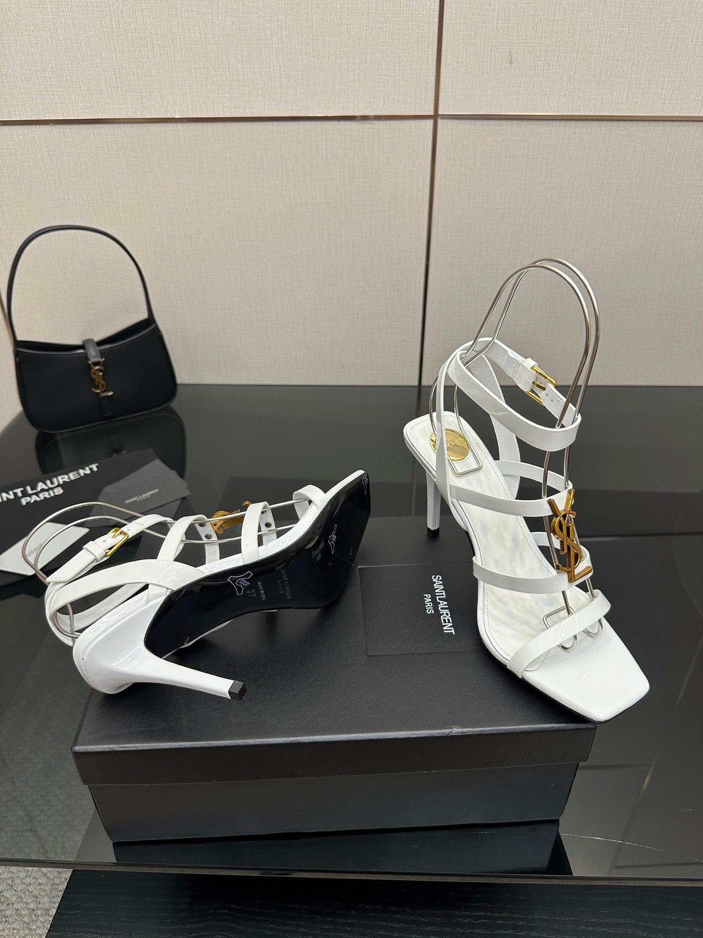 White high-heel strappy sandals with gold-tone buckles, shown from side angle.