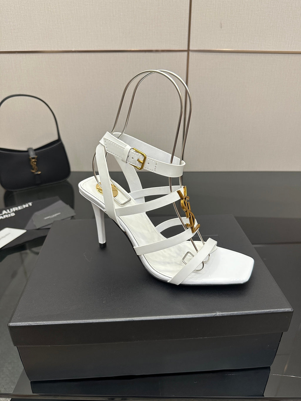 White high-heel sandals with ankle strap, layered straps, and gold-tone buckle detail.