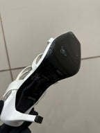 Black underside of a white high-heel sandal sole, showing brand markings.