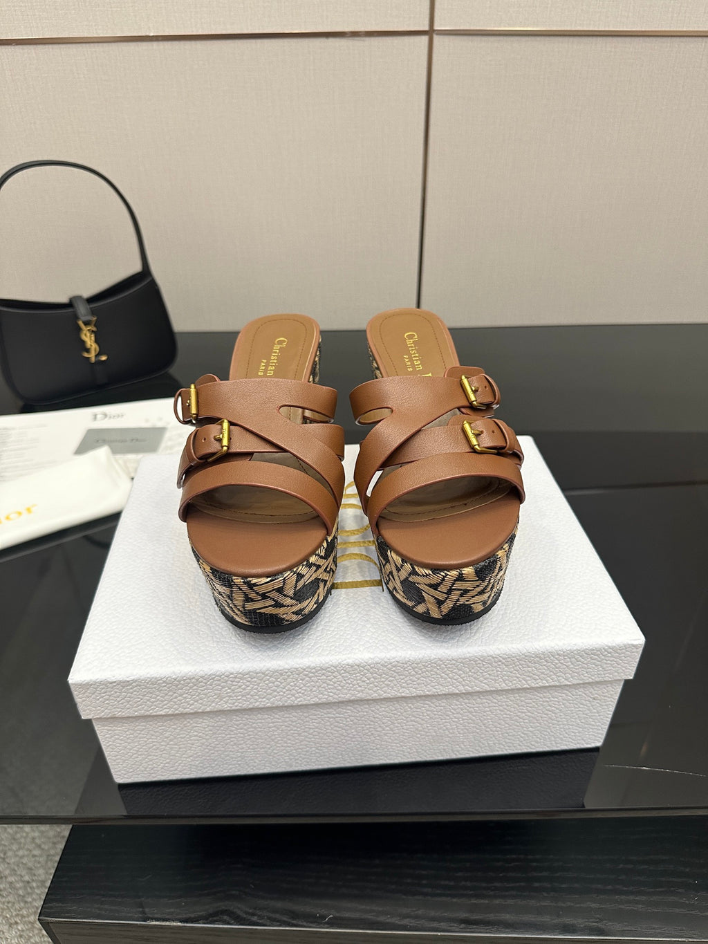 Tan leather platform slide sandals with gold buckle straps and woven wedge.