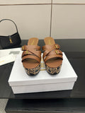Tan leather platform slide sandals with gold buckle straps and woven wedge.