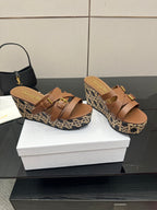Tan leather platform sandals with crisscross straps and gold buckles on woven wedge.