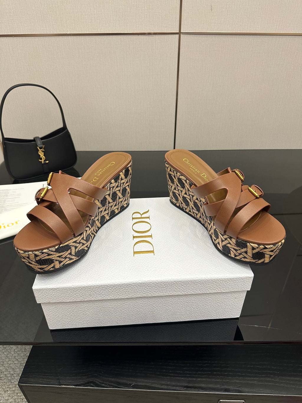 Tan leather platform sandals with adjustable gold buckles on patterned woven wedge.