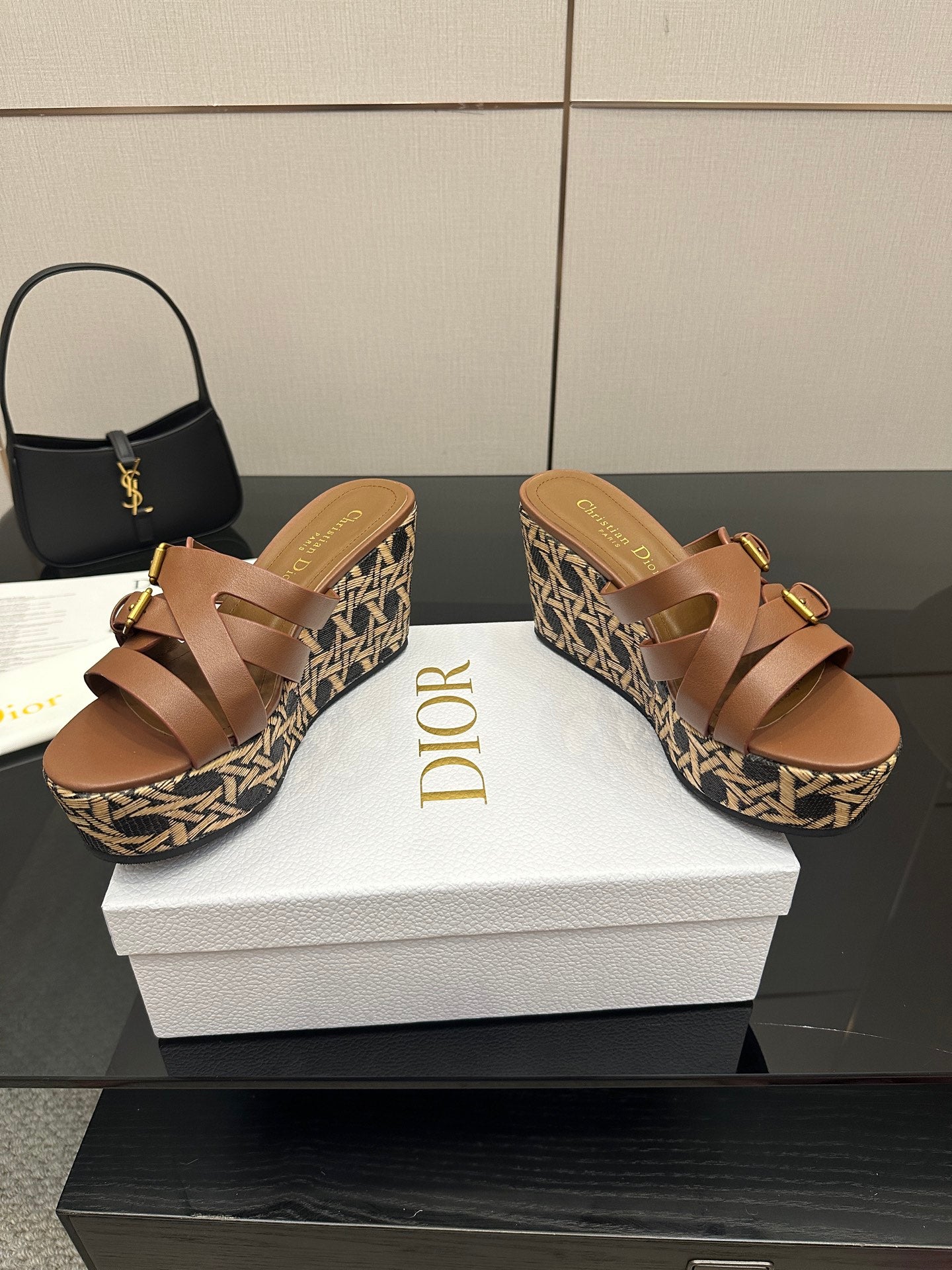 Tan leather platform sandals with adjustable gold buckles on patterned woven wedge.