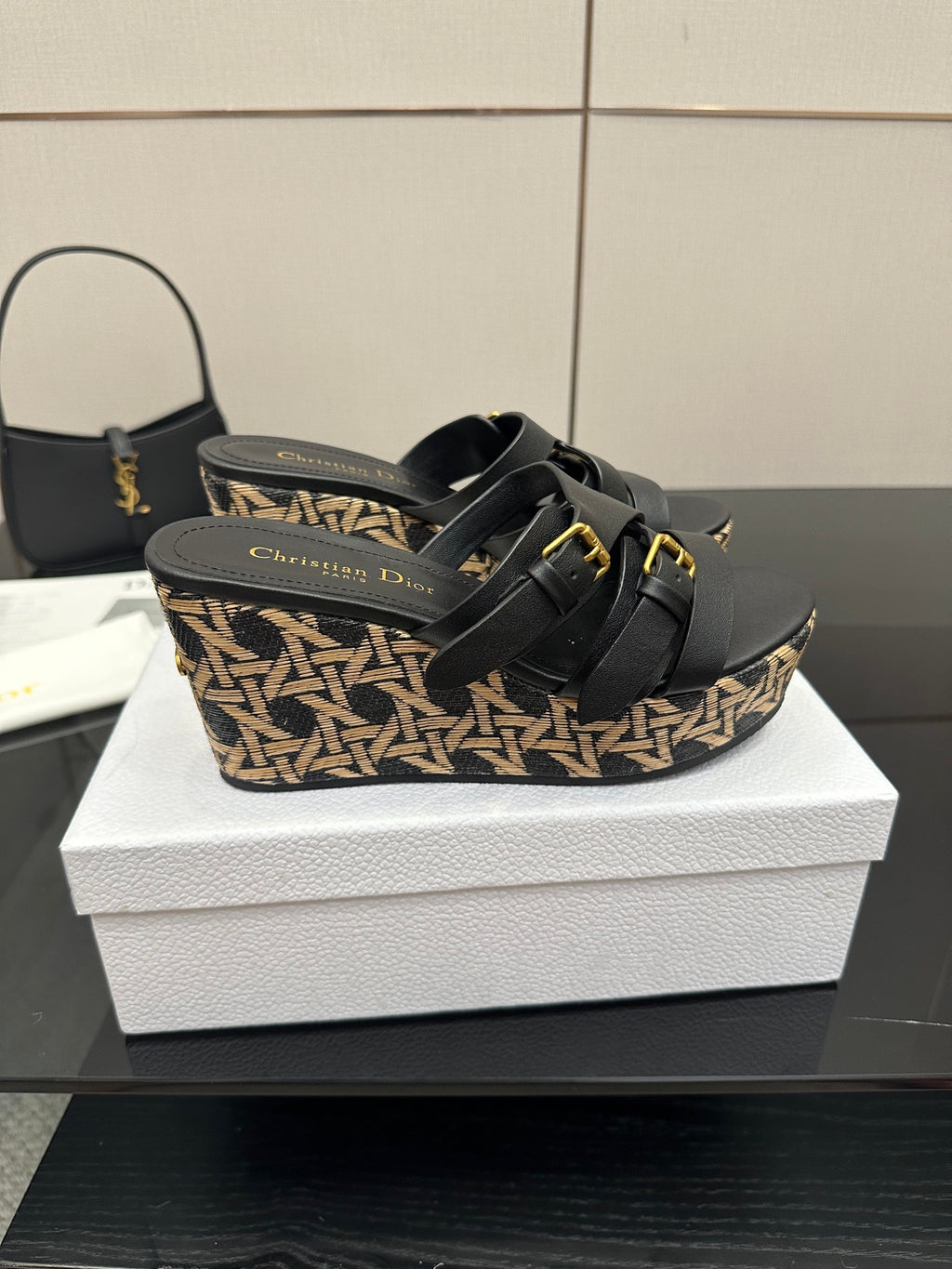 Black wedge slide sandals with gold buckles and patterned espadrille-style base
