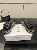 Black wedge sandals with wide straps, gold buckles, and patterned platform