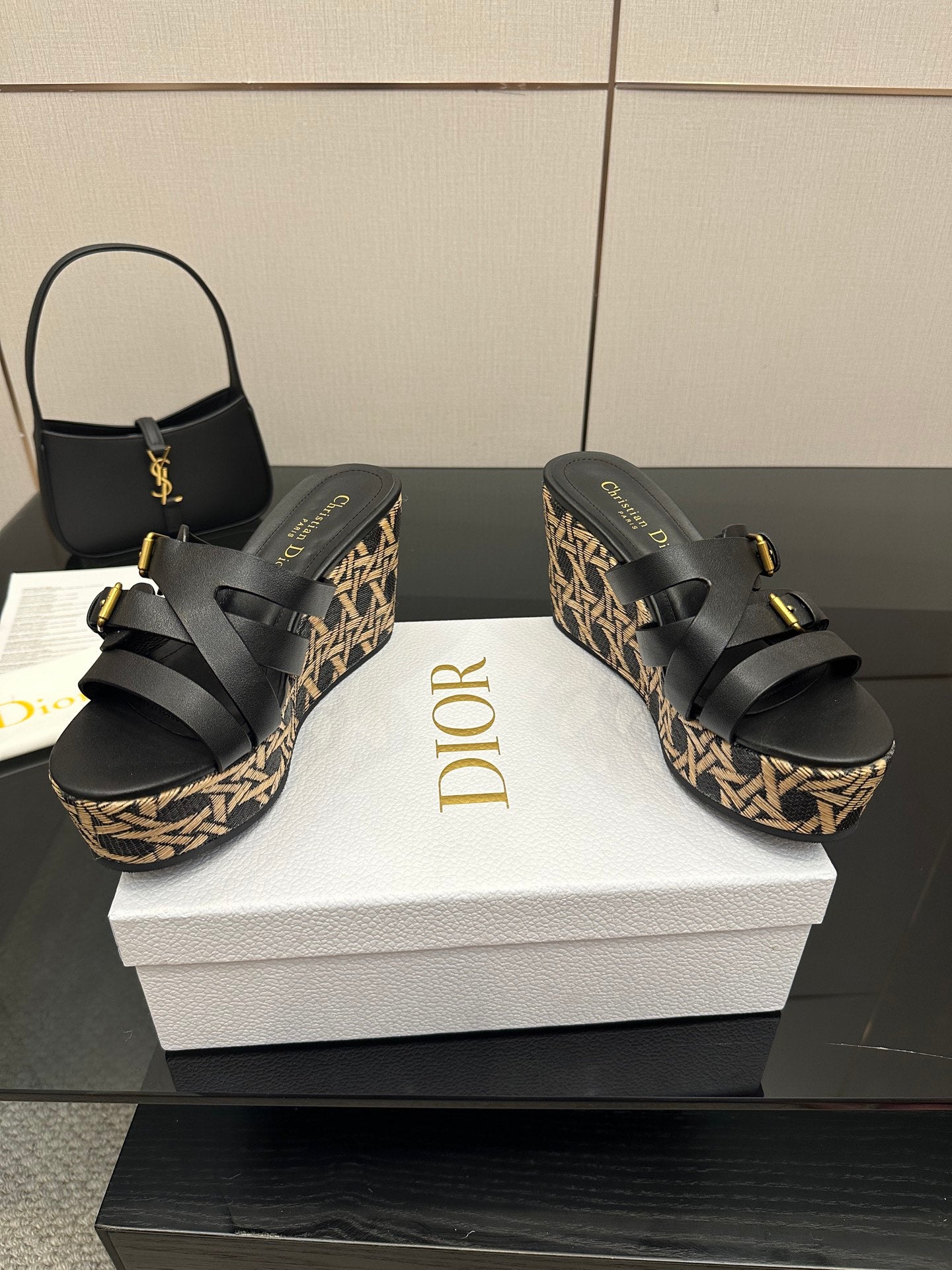 Black wedge sandals with wide straps, gold buckles, and patterned platform