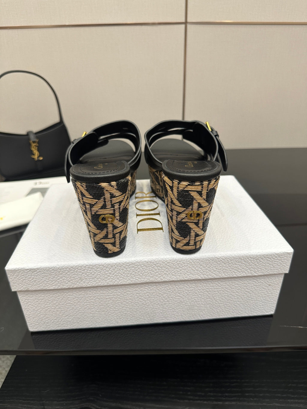 Back view of black slide wedge sandals with patterned heel and straps