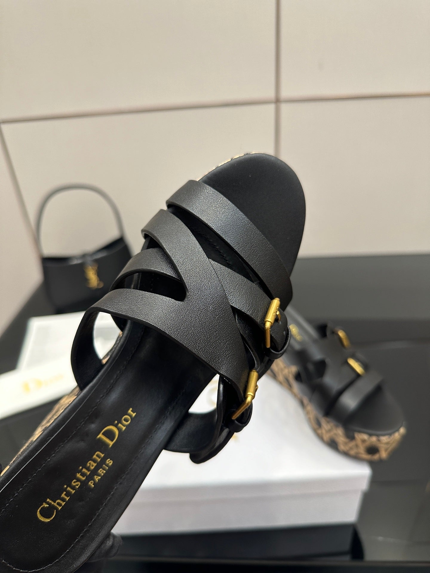 Black slide wedge sandal detail with gold buckles and patterned sidewall