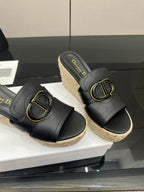 Close-up of black leather wedge sandals with gold buckle, espadrille sole