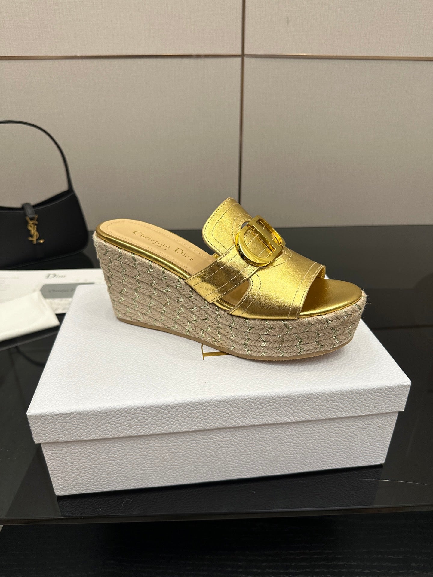 Single gold leather wedge mule with front buckle and jute espadrille wedge sole.