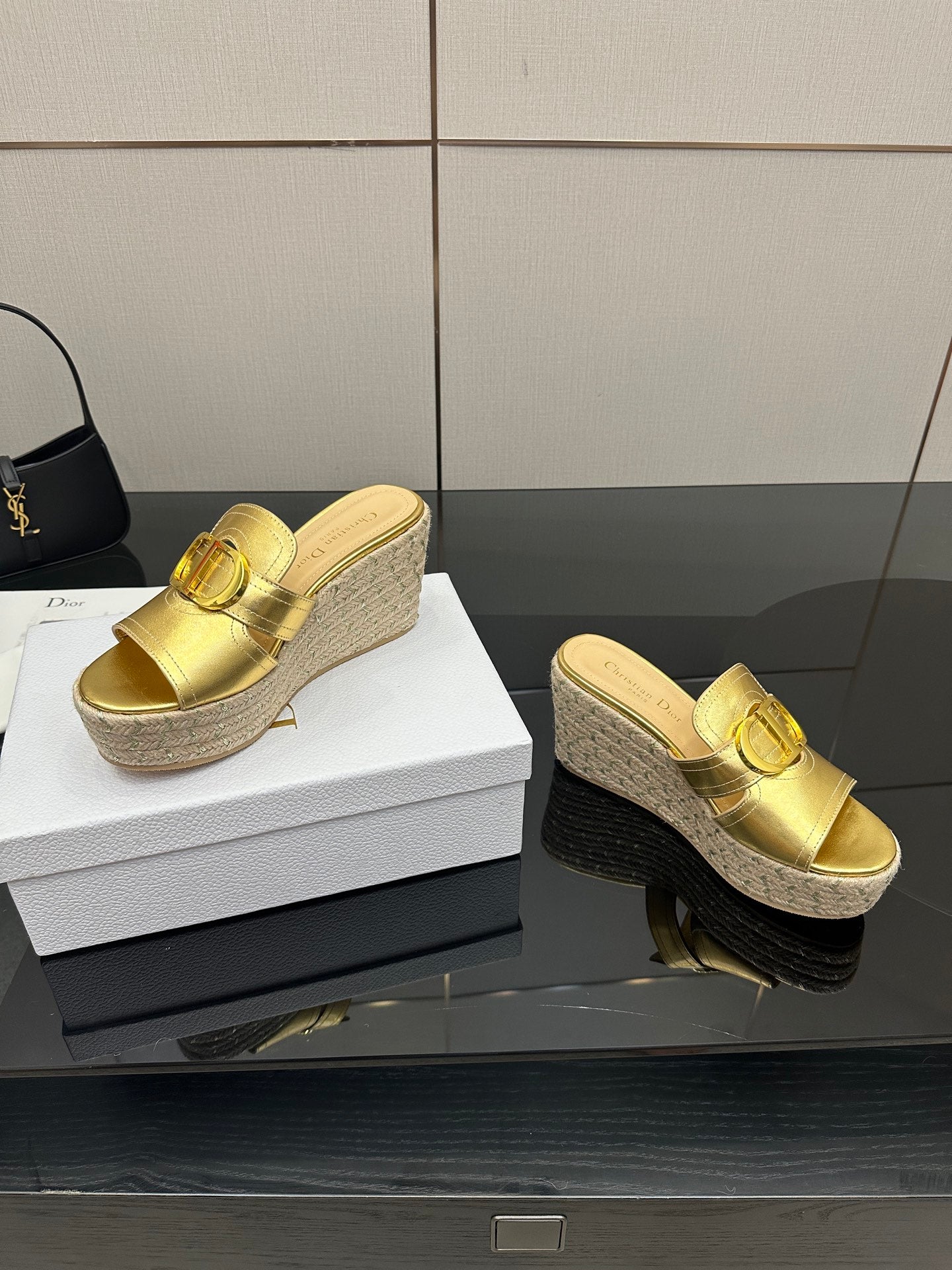 Gold leather wedge sandals with buckle strap, showing textured jute heel platform.