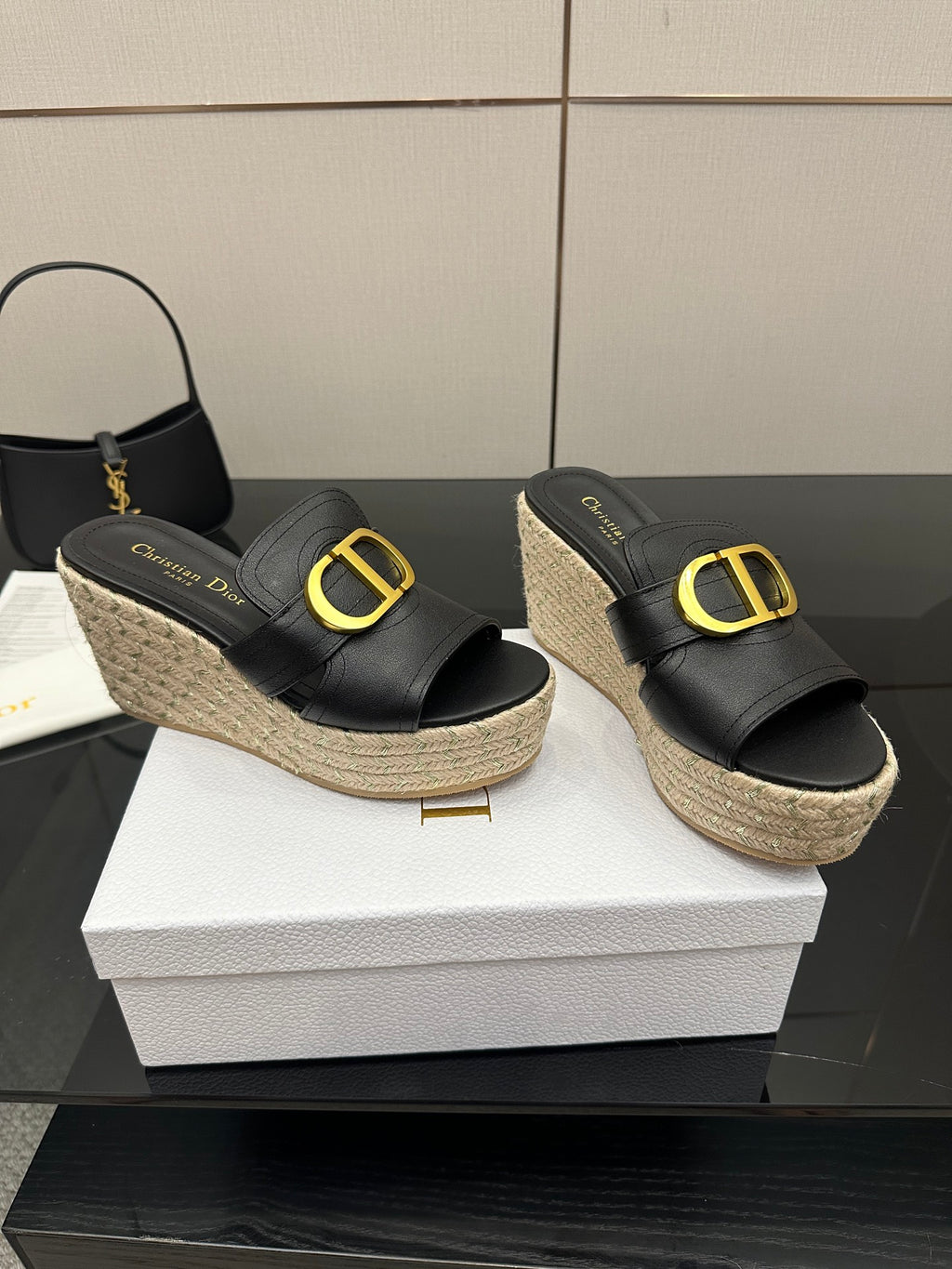 Pair of black platform slide mules with gold logo buckle and jute wedge sole.
