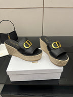 Pair of black platform slide mules with gold logo buckle and jute wedge sole.