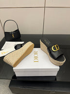 Black wedge slide sandals with gold logo buckle and jute sole, shown on box.