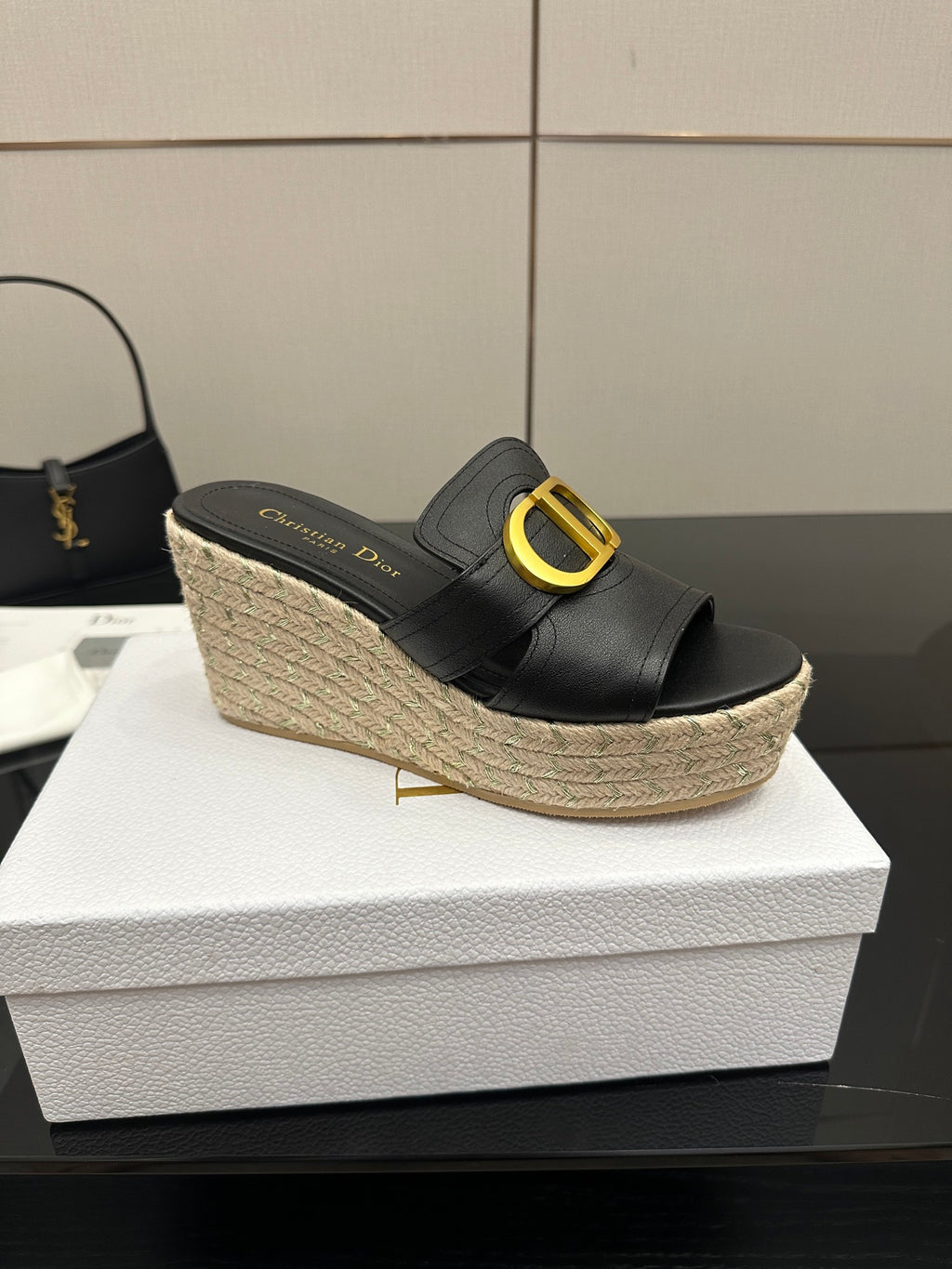 Black leather open-toe mule wedge with gold logo buckle and jute platform.