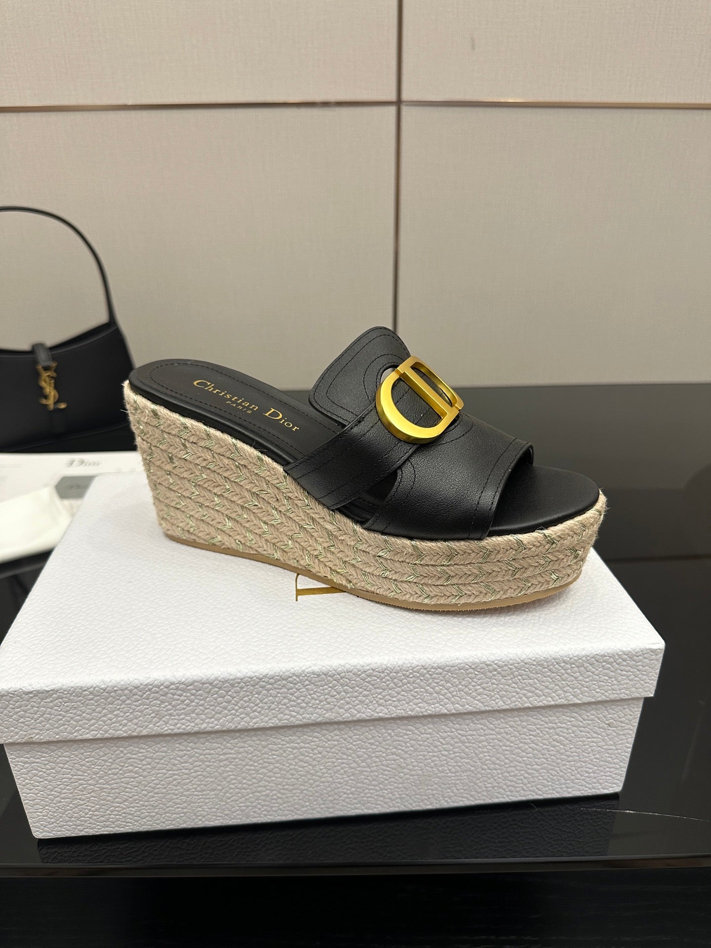 Black leather open-toe mule wedge with gold logo buckle and jute platform.