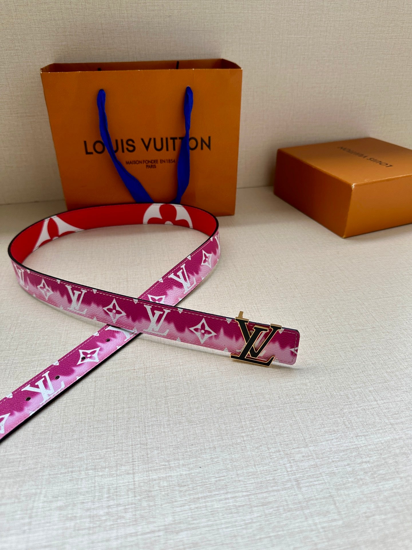 Louis Vuitton belt and loose strap ends with pink monogram pattern and LV buckle.