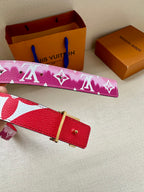 Louis Vuitton belt with pink monogram strap and red leather buckle tab.