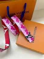 Louis Vuitton belt with pink monogram strap and gold-tone buckle on box.