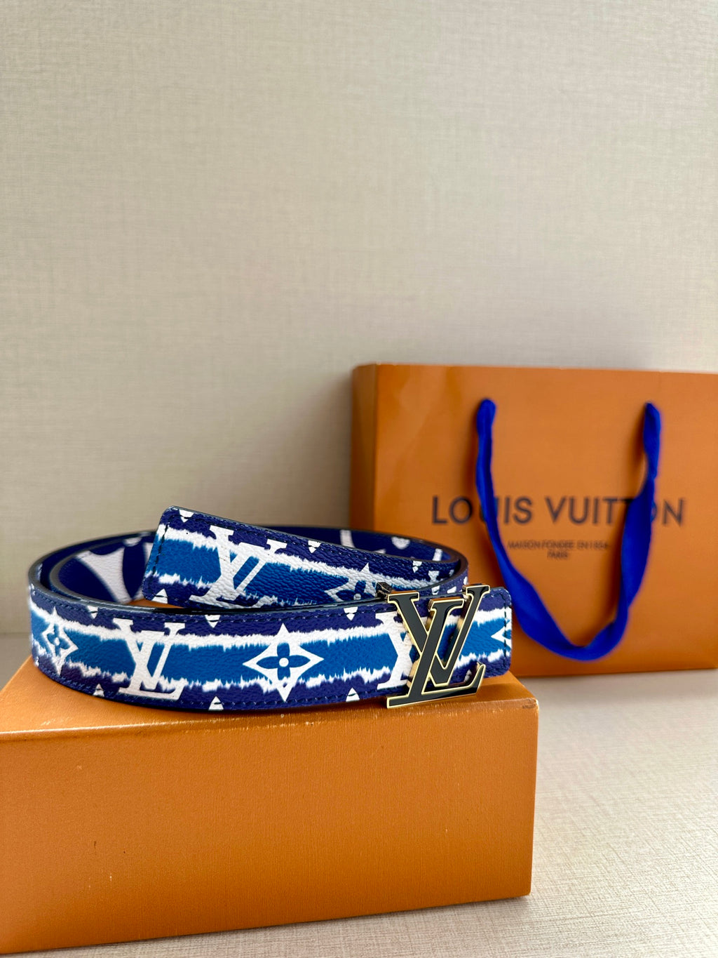 Blue and white monogram belt with gold buckle on flat lay