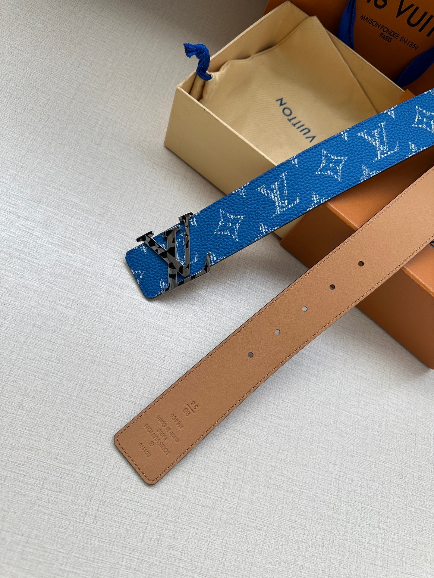 Blue monogram belt with gold-tone buckle paired with tan belt strap