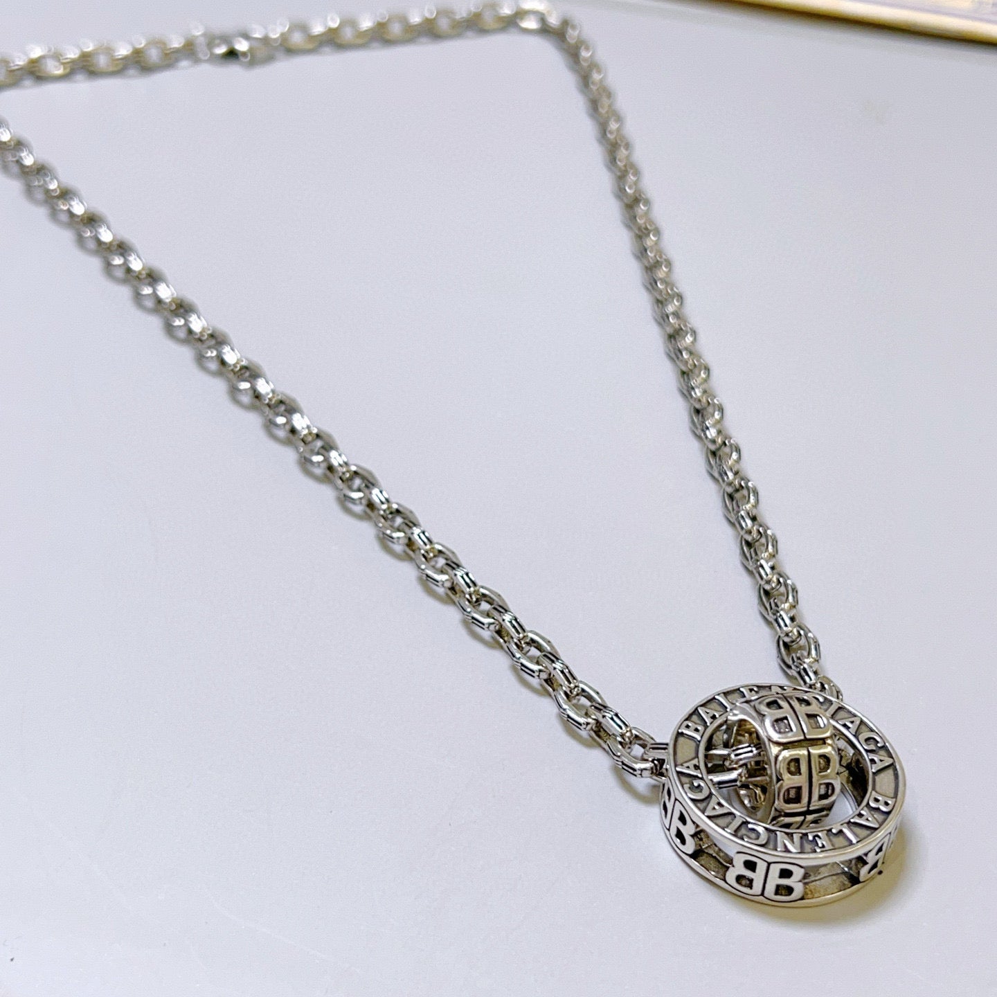 Silver-tone chain necklace with round Balenciaga monogram pendant, close-up