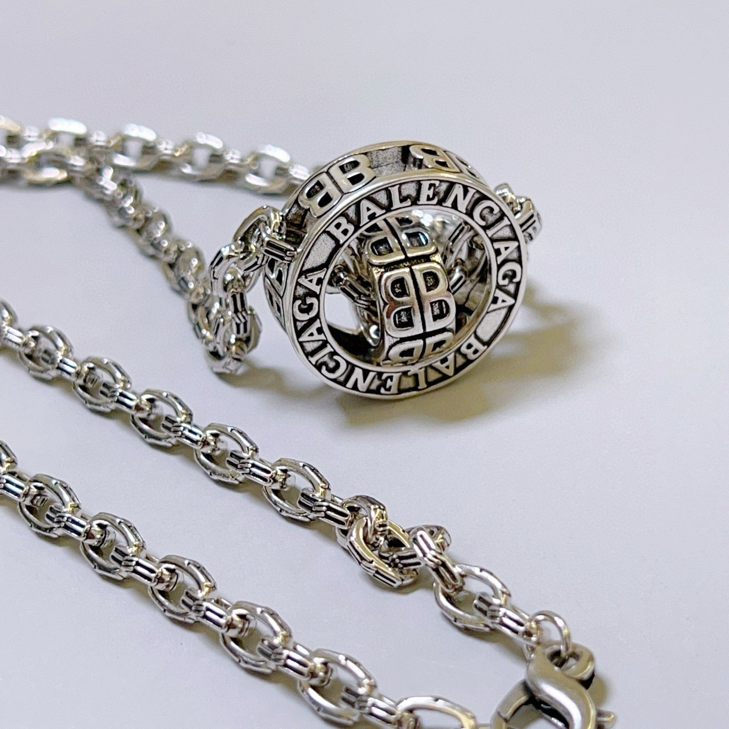 Silver-tone chain necklace with round Balenciaga monogram pendant, close-up