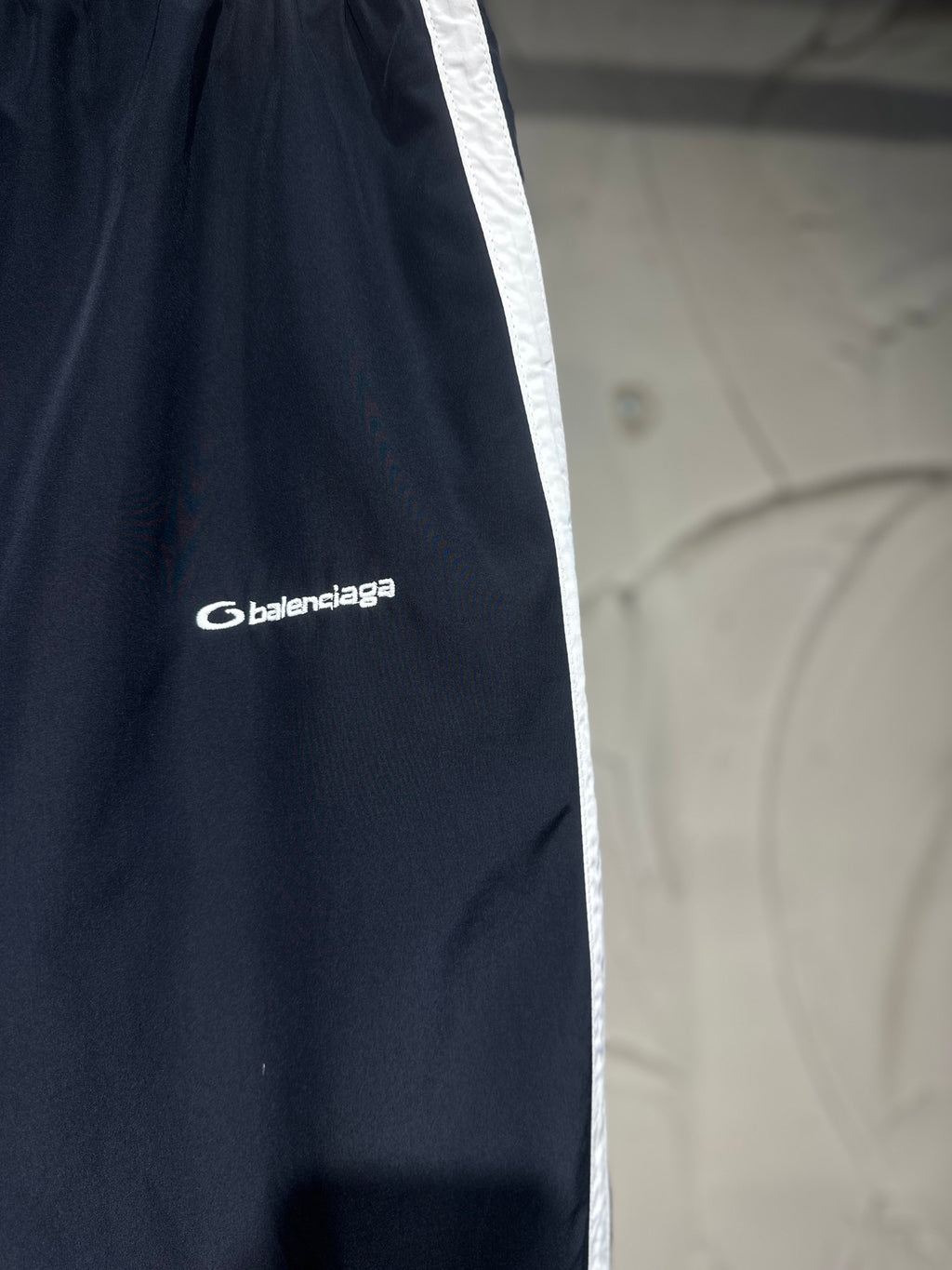 Balenciaga pants side with white stripe and Balenciaga logo on dark fabric
