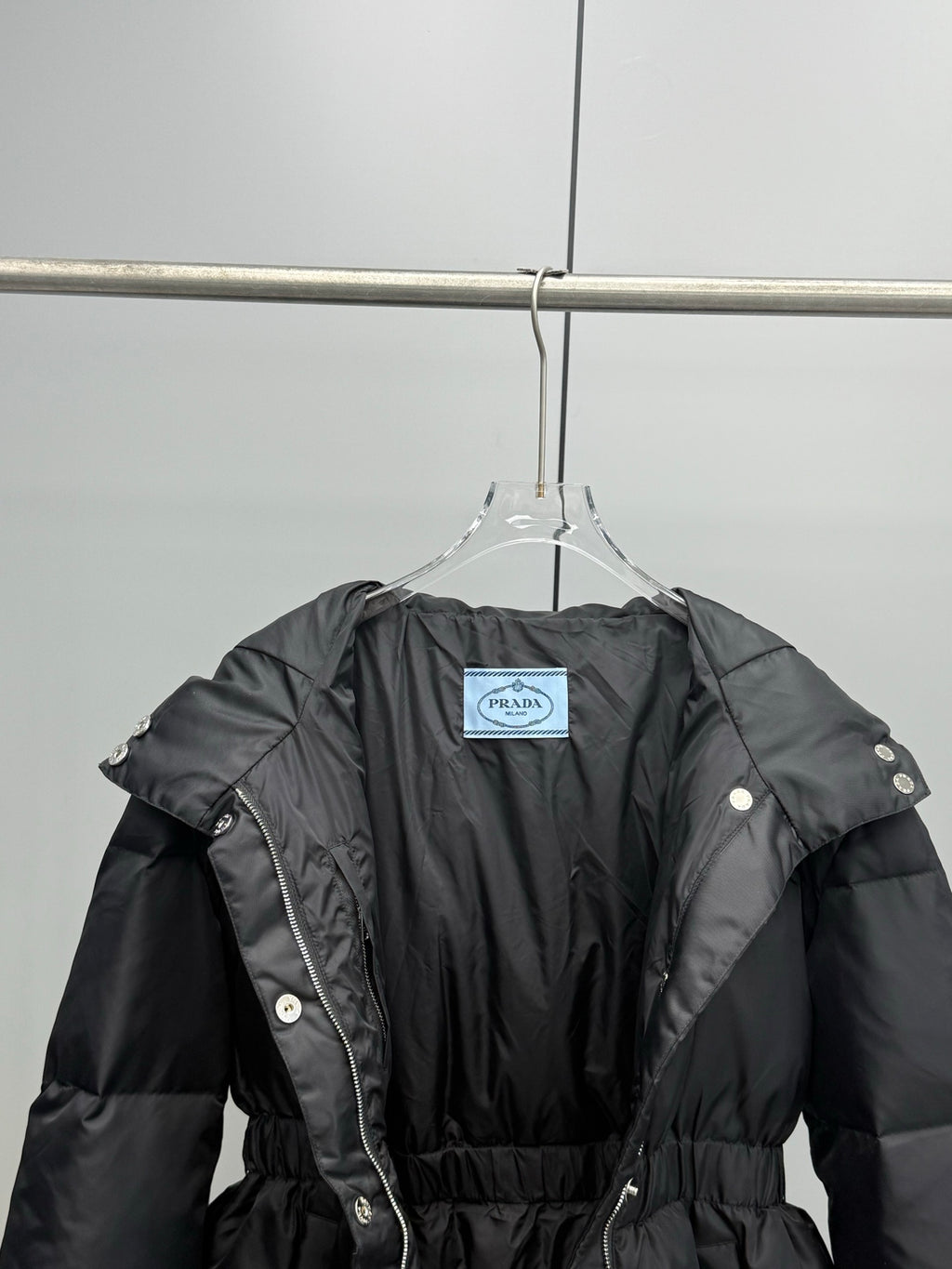 Prada black puffer coat with belt and hood, front view with interior tag