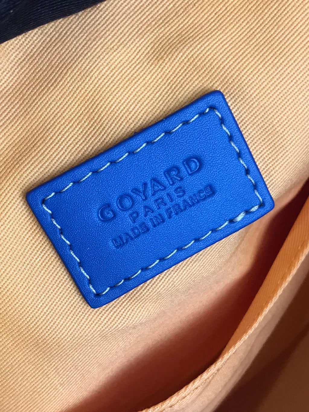Blue leather brand patch with Goyard Paris text on bag interior lining.