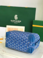 Blue Goyard-pattern barrel bag with zip top and short carry handle.