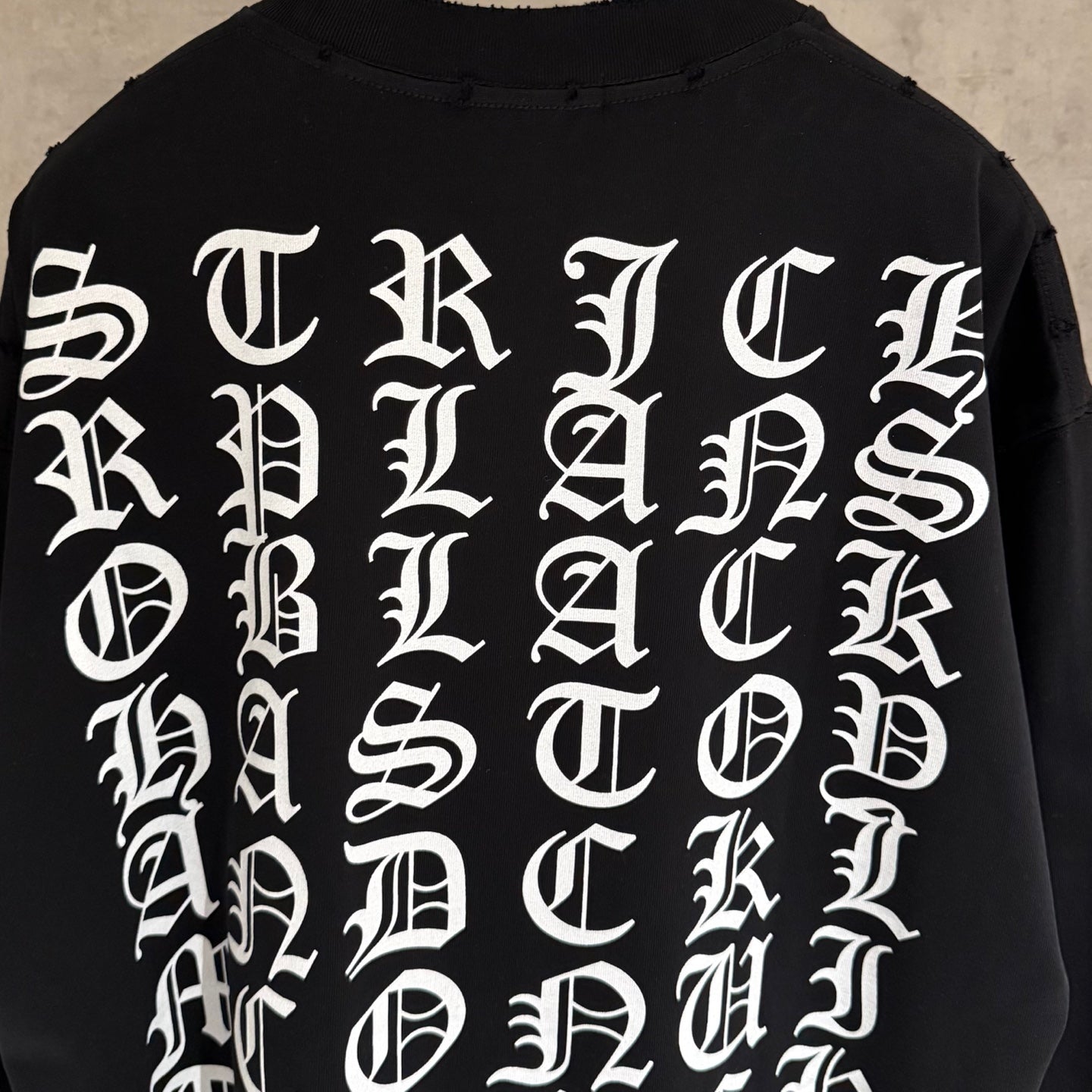 Black long-sleeve sweatshirt close-up of white back letter graphic
