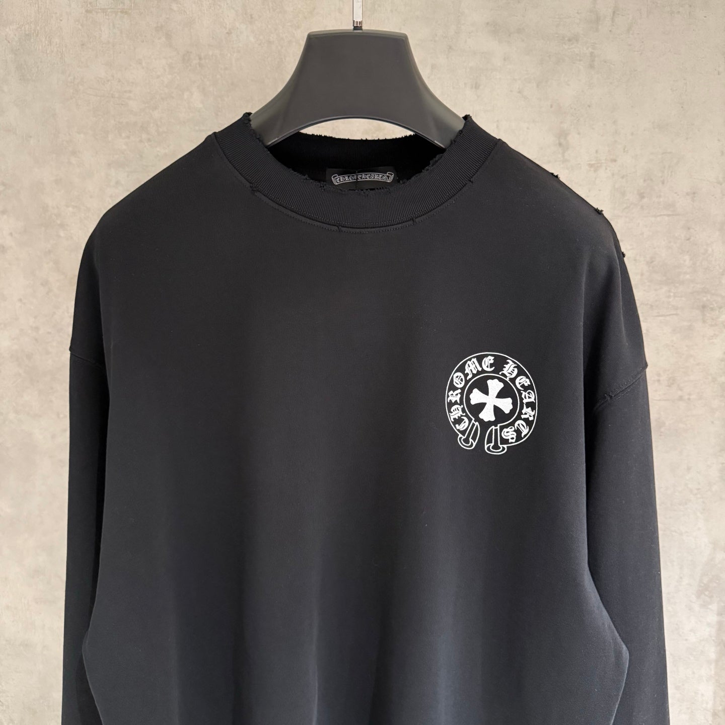 Black long-sleeve crewneck sweatshirt with small circular chest logo