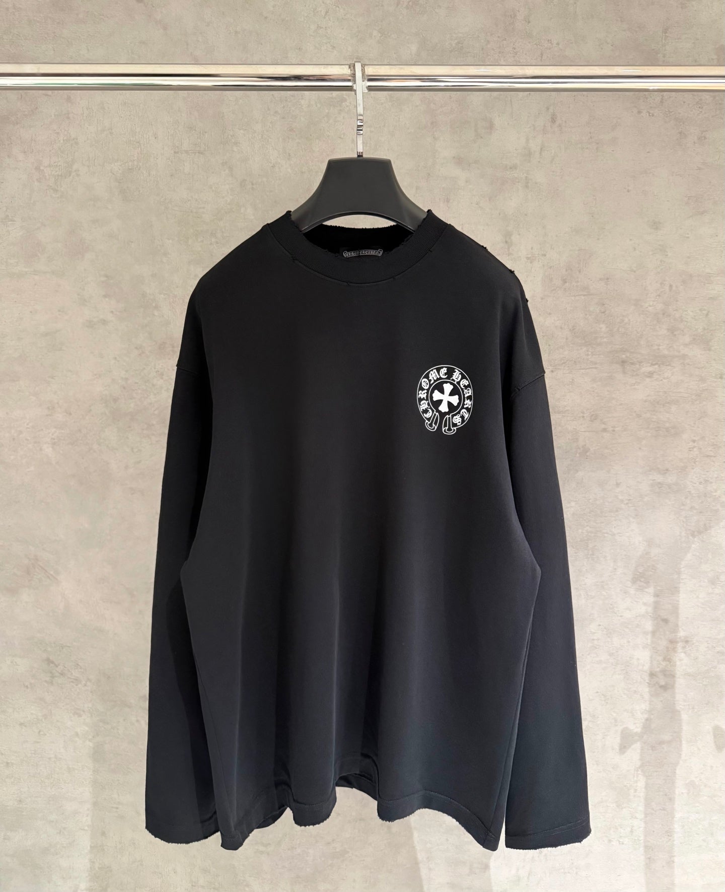 Black long-sleeve crewneck sweatshirt with small circular chest logo patch