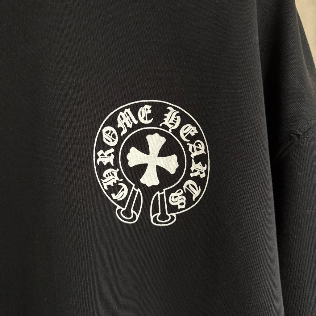 Black long-sleeve sweatshirt close-up of circular cross-style logo emblem