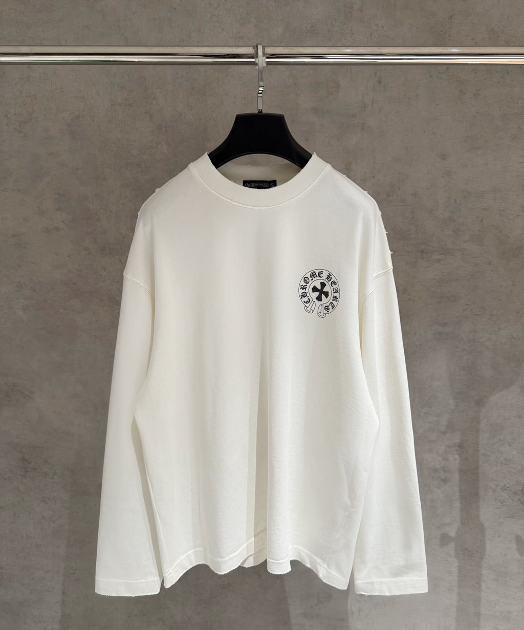 White long-sleeve shirt on hanger, small chest emblem print