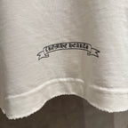 White long-sleeve shirt hem area with small printed ribbon text