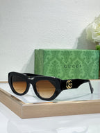 Gucci sunglasses, black frames with brown lenses and gold GG logo on temple.