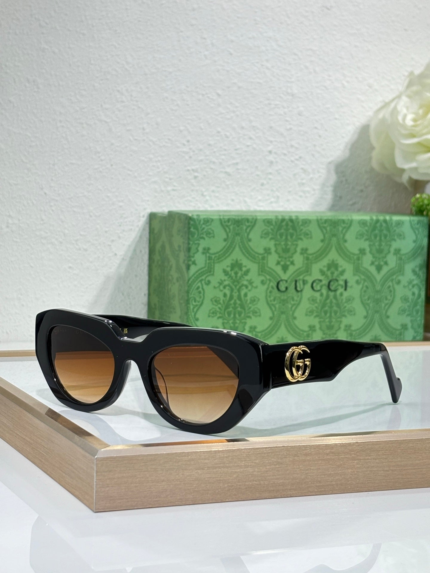Gucci sunglasses, black frames with brown lenses and gold GG logo on temple.
